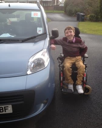 wheelchair user Conor Smyth beside his car after he passed his driving test