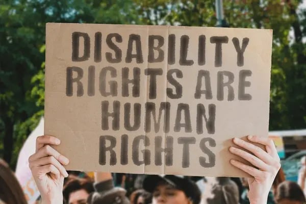 Photograph of an activist holding a sign saying 'Disability Rights are Human Rights'