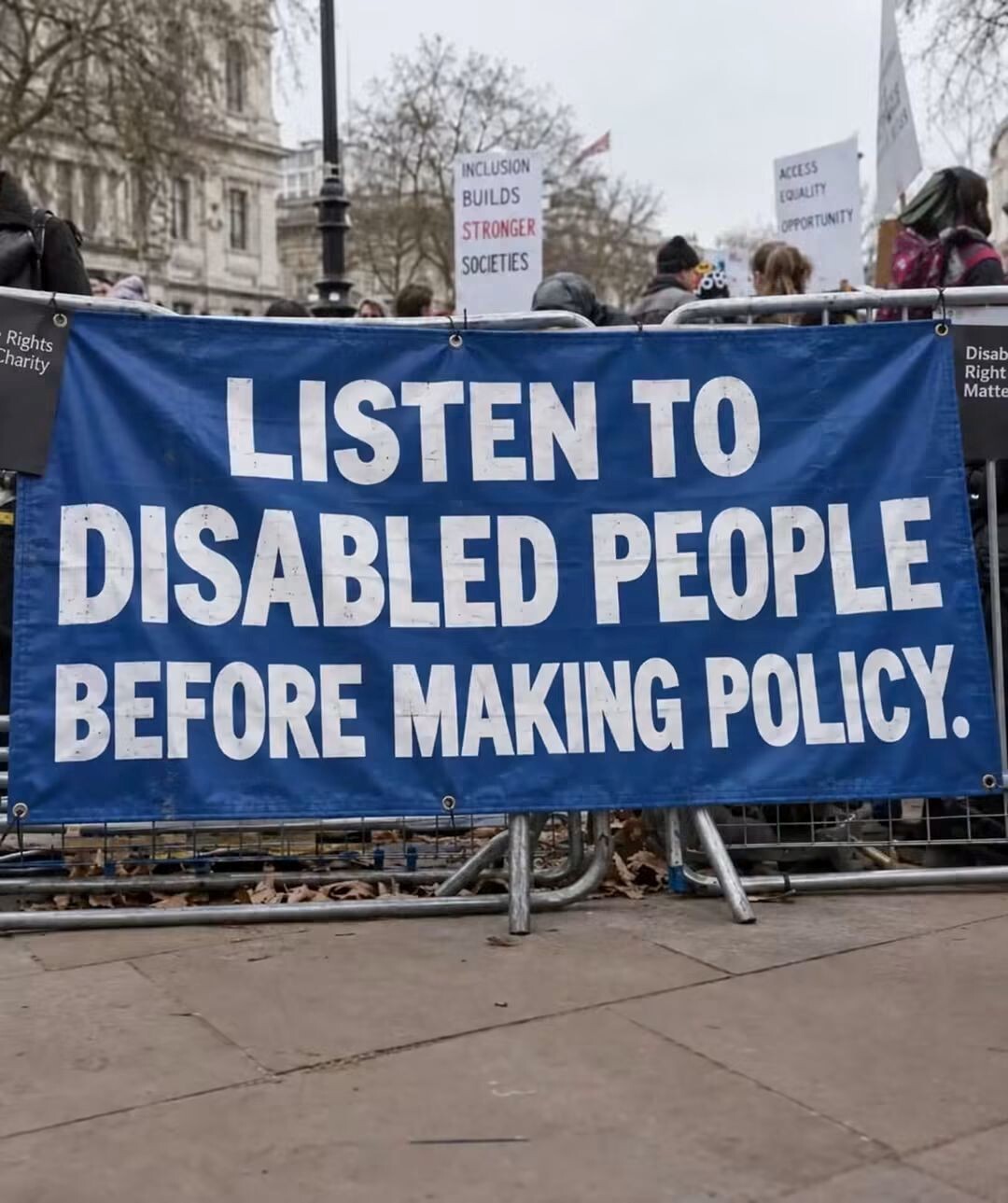 Image with a protest banner that says 'Listen to Disabled People Before making Policy